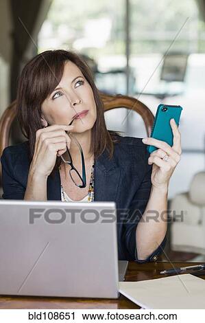 Caucasian businesswoman holding cell phone and looking up View Large Photo Image Stock Image - Caucasian businesswoman holding cell phone and looking up. Fotosearch