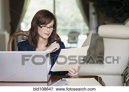 Stock Photo - Caucasian businesswoman looking at paperwork. Fotosearch