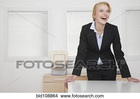 Caucasian businesswoman standing at desk in office View Large Photo Image Picture - Caucasian businesswoman standing at desk in office. Fotosearch