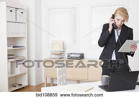Stock Photo - Caucasian businesswoman talking on phone in office. Fotosearch