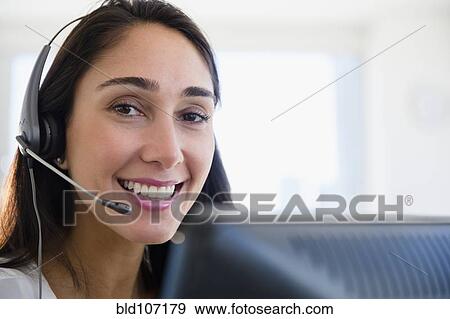 Stock Photo - Caucasian businesswoman wearing headset at desk. Fotosearch