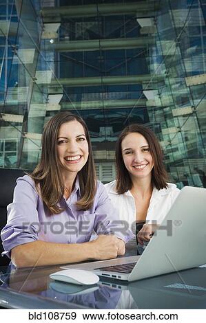 Caucasian businesswomen smiling at desk View Large Photo Image Stock Photo - Caucasian businesswomen smiling at desk. Fotosearch