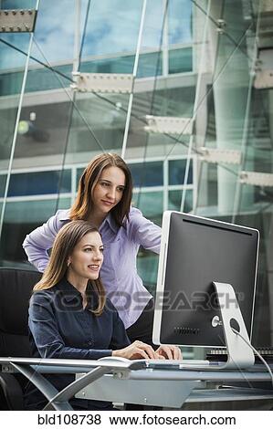 Stock Photo - Caucasian businesswomen working at computer. Fotosearch