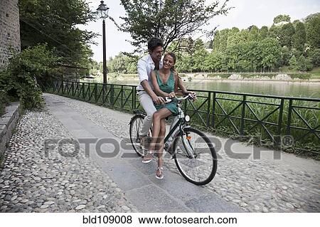 Caucasian couple riding bicycle together View Large Photo Image Stock Photo - Caucasian couple riding bicycle together. Fotosearch