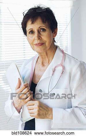 Picture - Caucasian doctor holding clipboard in office. Fotosearch