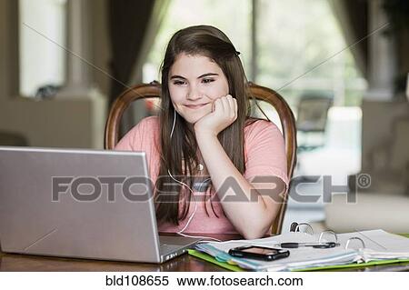 Stock Photography - Caucasian girl using laptop and listening to mp3 player. Fotosearch