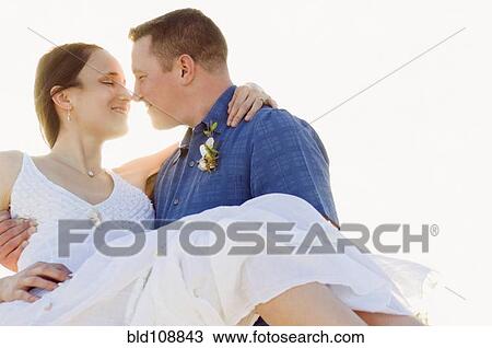 Stock Image - Caucasian man holding wife outdoors. Fotosearch