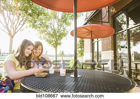 Stock Photo - Caucasian mother and daughter looking at cell phone together. Fotosearch