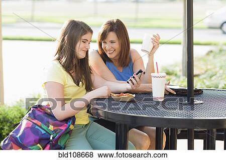 Stock Photo - Caucasian mother and daughter looking at cell phone together. Fotosearch