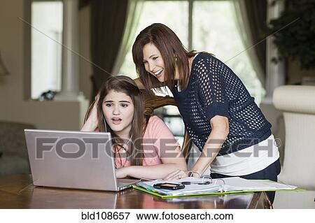 Stock Photo - Caucasian mother helping daughter with homework. Fotosearch
