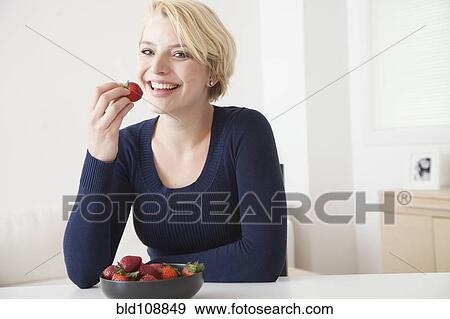 Caucasian woman eating strawberries in kitchen View Large Photo Image Stock Photo - Caucasian woman eating strawberries in kitchen. Fotosearch