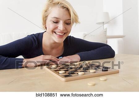 Stock Image - Caucasian woman playing checkers. Fotosearch