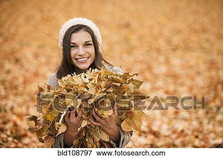 Stock Photo - Caucasian woman playing in autumn leaves. Fotosearch