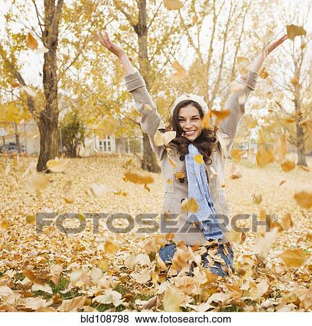 Stock Photo - Caucasian woman playing in autumn leaves. Fotosearch