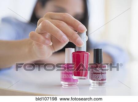 Stock Photo - Caucasian woman selecting bottle of nail polish. Fotosearch