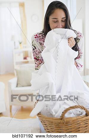 Stock Image - Caucasian woman smelling fresh laundry. Fotosearch