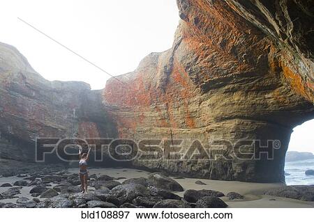 Stock Photo - Caucasian woman stretching in rock formations. Fotosearch