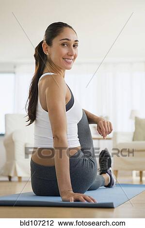 Stock Image - Caucasian woman stretching on exercise mat. Fotosearch