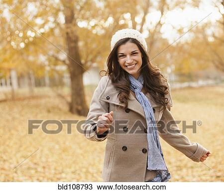 Stock Image - Caucasian woman walking in autumn leaves. Fotosearch