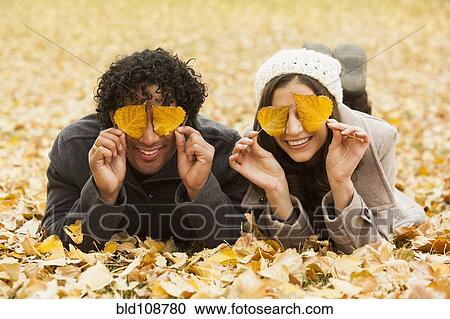 Stock Image - Couple playing in autumn leaves. Fotosearch