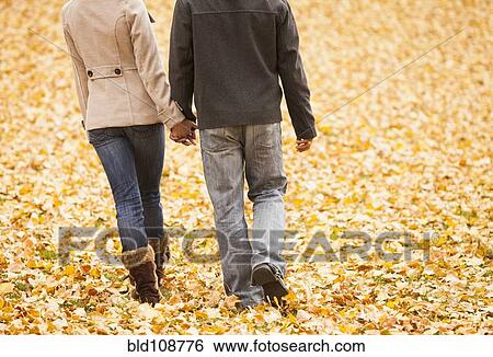 Couple walking in autumn leaves View Large Photo Image Stock Photograph - Couple walking in autumn leaves. Fotosearch