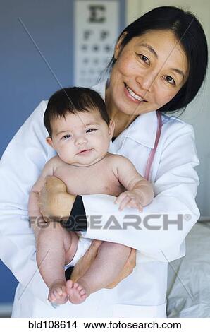 Picture - Doctor holding baby in office. Fotosearch