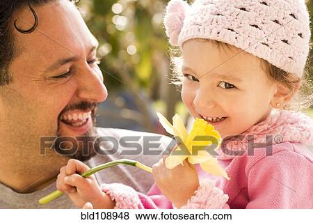 Stock Photo - Father smiling at daughter with flower. Fotosearch