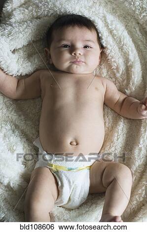 Stock Photograph - Hispanic baby laying on rug. Fotosearch
