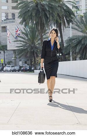 Hispanic businesswoman walking and talking on cell phone View Large Photo Image Stock Photograph - Hispanic businesswoman walking and talking on cell phone. Fotosearch
