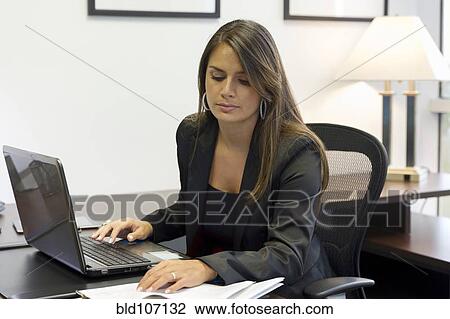 Stock Image - Hispanic businesswoman working at desk. Fotosearch