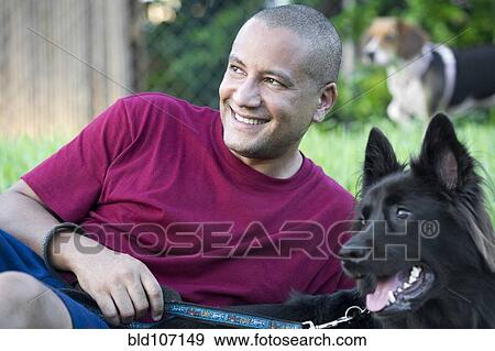 Hispanic man relaxing with dog in park View Large Photo Image Stock Photo - Hispanic man relaxing with dog in park. Fotosearch