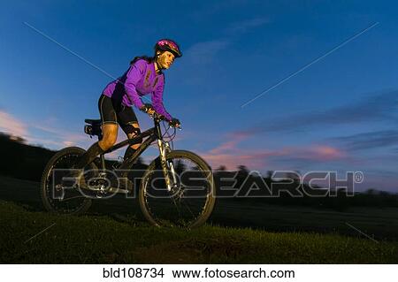Picture - Hispanic teenager riding bicycle in woods. Fotosearch