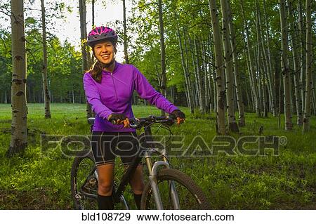 Stock Photo - Hispanic teenager riding bicycle in woods. Fotosearch