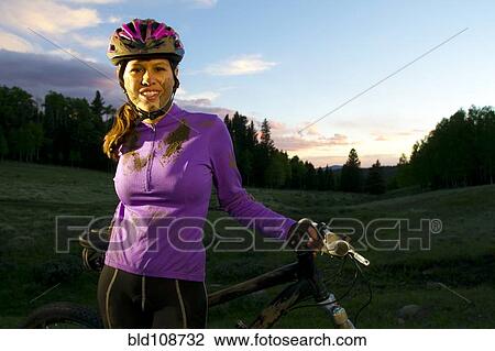 Stock Image - Hispanic teenager standing with bicycle in woods. Fotosearch