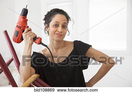 Stock Photo - Hispanic woman holding power drill. Fotosearch