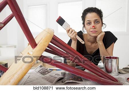 Stock Image - Hispanic woman painting chair. Fotosearch