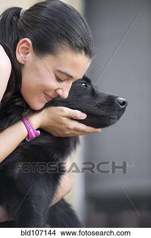 Picture - Hispanic woman petting dog. Fotosearch