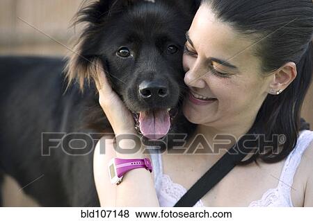 Stock Photo - Hispanic woman petting dog. Fotosearch