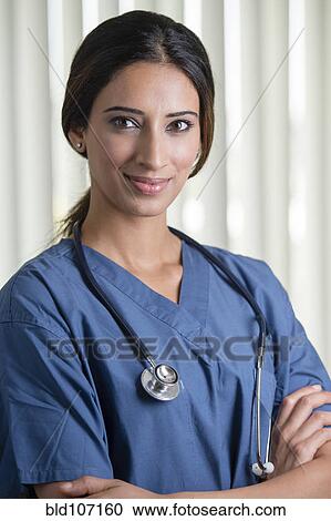 Stock Image - Indian nurse standing with arms crossed. Fotosearch