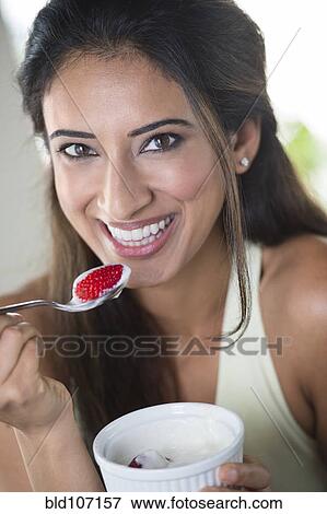 Stock Photo - Indian woman eating fruit. Fotosearch