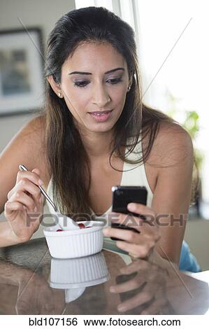 Indian woman using cell phone and eating View Large Photo Image Stock Photograph - Indian woman using cell phone and eating. Fotosearch