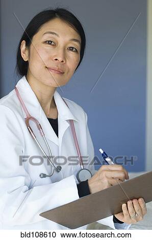 Stock Image - Japanese doctor writing on clipboard. Fotosearch