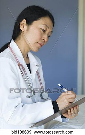 Stock Photo - Japanese doctor writing on clipboard. Fotosearch