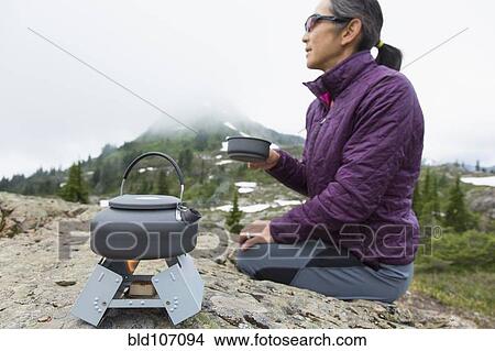 Picture - Japanese woman drinking coffee at campsite. Fotosearch