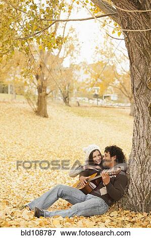 Man playing guitar for girlfriend in autumn leaves View Large Photo Image Stock Photo - Man playing guitar for girlfriend in autumn leaves. Fotosearch