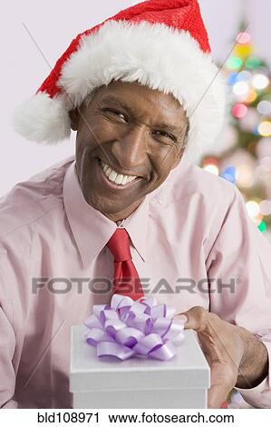 Stock Image - Mixed race businessman giving Christmas present. Fotosearch