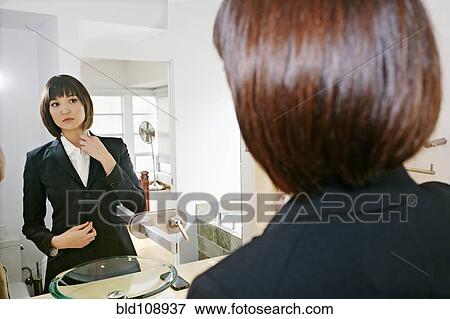 Mixed race businesswoman adjusting her collar in mirror View Large Photo Image Stock Photo - Mixed race businesswoman adjusting her collar in mirror. Fotosearch
