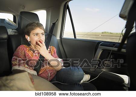 Stock Photo - Mixed race girl eating apple in car. Fotosearch