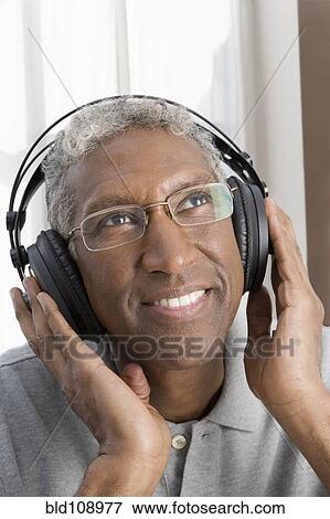 Stock Photo - Mixed race man listening to headphones. Fotosearch