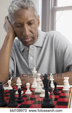 Stock Image - Mixed race man playing chess. Fotosearch